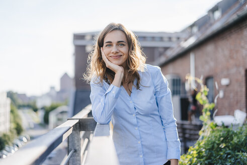 Businesswoman standing on her urban rooftop garden - KNSF02800