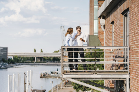 Geschäftsleute, die auf einem Balkon stehen und ein Smartphone benutzen, lizenzfreies Stockfoto