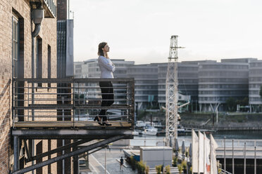 Businesswoman standing on a balcony, with eyes closed - KNSF02810