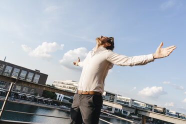 Happy businessman standing on balcony, with arms out - KNSF02814