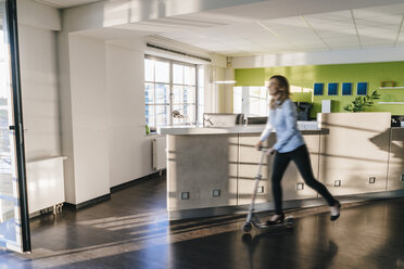 Geschäftsfrau benutzt Kickboard im Büro - KNSF02817