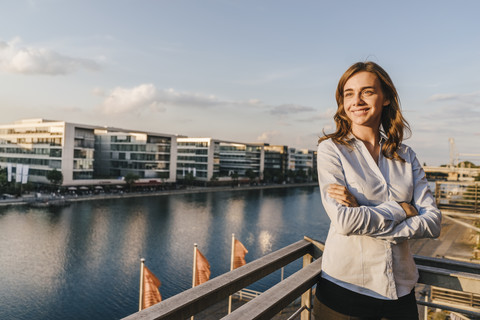 Geschäftsfrau steht auf der Terrasse eines Industriegebäudes, lizenzfreies Stockfoto