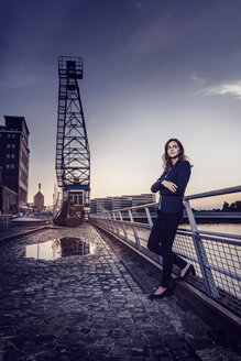 Businesswoman standing at wet inner harbor, thinking - KNSF02819