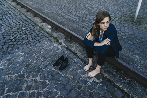 Barefoot businesswoman sitting on rail stock photo
