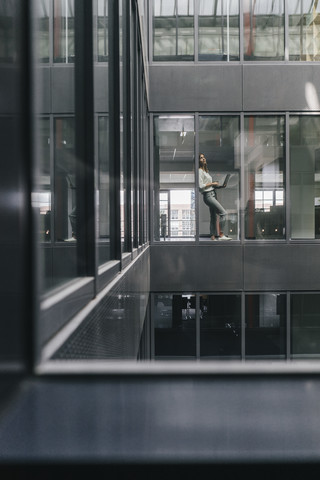 Frau am Bürofenster stehend, lizenzfreies Stockfoto