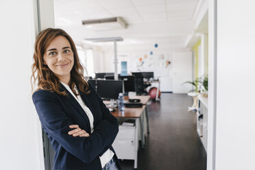 Confident businesswoman standing smiling in office - KNSF02843