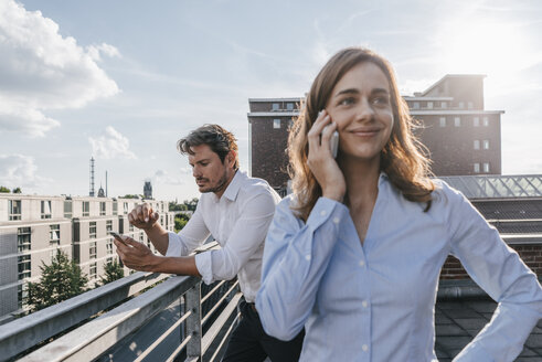 Geschäftsleute, die auf einem Balkon stehen und ein Smartphone benutzen - KNSF02864