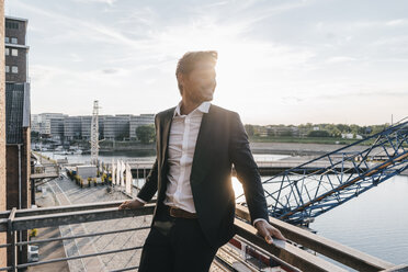 Successful businessman standing on balcony - KNSF02869