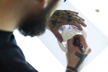 Tattoo artist designing motif on light table in studio - IGGF00161