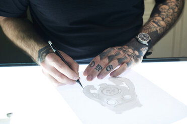 Tattoo artist designing motif on light table in studio - IGGF00165