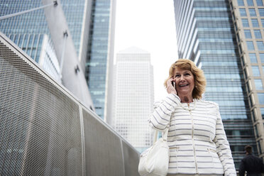 UK, London, lächelnde ältere Geschäftsfrau am Telefon in der Stadt - IGGF00186