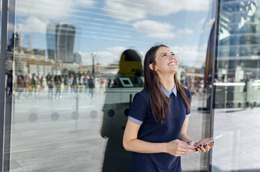 UK, London, happy woman with smartphone in the city - MGOF03612