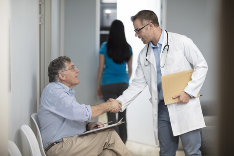 Arzt beim Händeschütteln mit einem Patienten in einer Arztpraxis, lizenzfreies Stockfoto