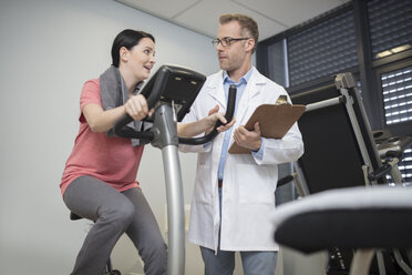 Arzt im Gespräch mit einem Patienten auf einem Trainingsgerät - ZEF14550