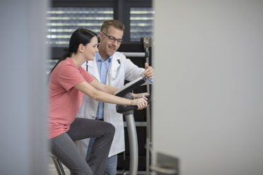 Lächelnder Arzt und Patient am Trainingsgerät - ZEF14554