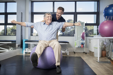 Älterer Mann trainiert mit einem Fitnessball in einer Physiotherapiepraxis - ZEF14570