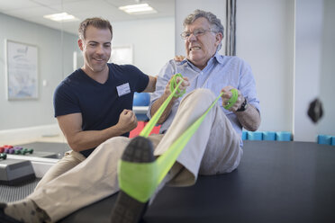 Senior man exercising with resistance band at physio's practice - ZEF14571