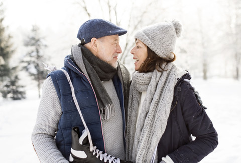 Älteres Paar mit Schlittschuhen in Winterlandschaft, lizenzfreies Stockfoto