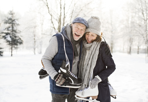Happy senior couple with ice skates in winter landscape stock photo