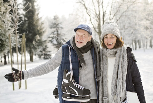 Glückliches Seniorenpaar mit Schlittschuhen in Winterlandschaft - HAPF02131