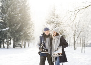 Glückliches älteres Paar mit Schlittschuhen in einer Winterlandschaft - HAPF02133