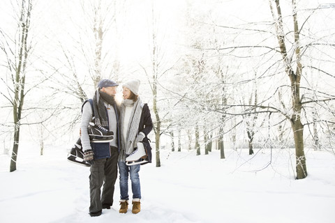 Älteres Paar mit Schlittschuhen im Winterwald, lizenzfreies Stockfoto