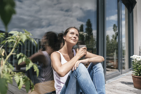 Lächelnde Frau entspannt sich auf dem Balkon, lizenzfreies Stockfoto