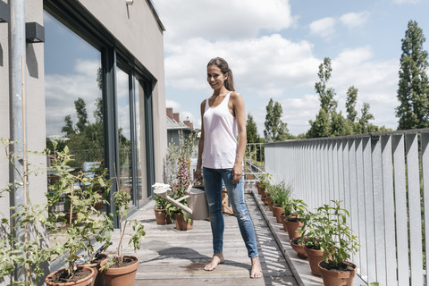 Smiling woman on balcony holding watering can stock photo