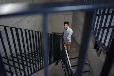 Smiling young man standing in staircase - JOSF01566