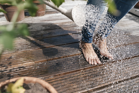 Frau mit Gießkanne, die Wasser über ihre Füße gießt, lizenzfreies Stockfoto