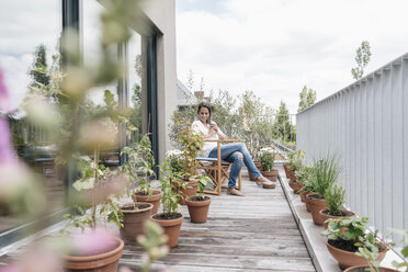 Smiling woman relaxing on balcony - JOSF01572