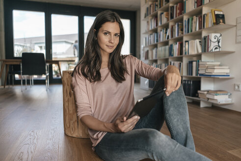 Portrait of woman relaxing at home holding tablet - JOSF01574