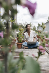 Woman sitting on balcony using laptop - JOSF01577