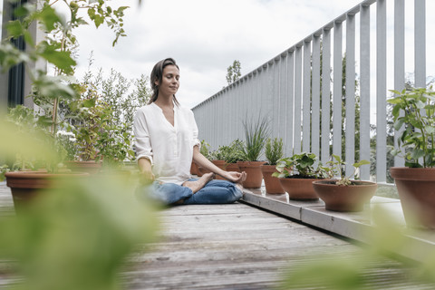 Frau sitzt auf Balkon und übt Yoga, lizenzfreies Stockfoto