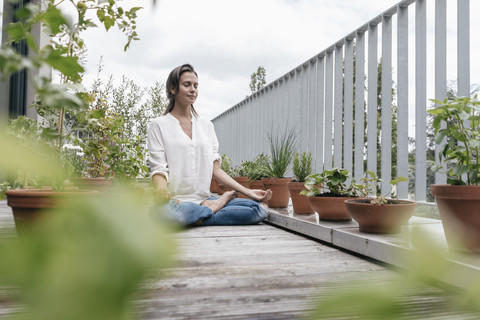 Woman sitting on balcony practicing yoga stock photo