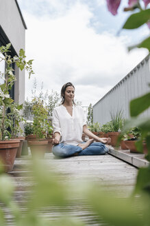 Frau sitzt auf Balkon und übt Yoga - JOSF01579