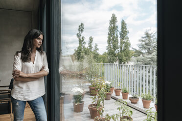 Woman at home looking out of window - JOSF01580