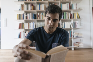 Young man reading book at home - JOSF01584
