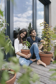 Glückliches Paar mit Pflanzen, das sich auf dem Balkon entspannt - JOSF01590