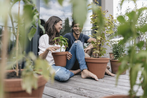 Happy couple with plants relaxing on balcony - JOSF01591