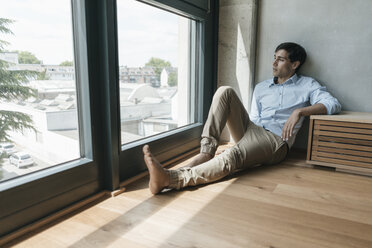 Mann sitzt auf dem Boden und schaut aus dem Fenster - JOSF01600