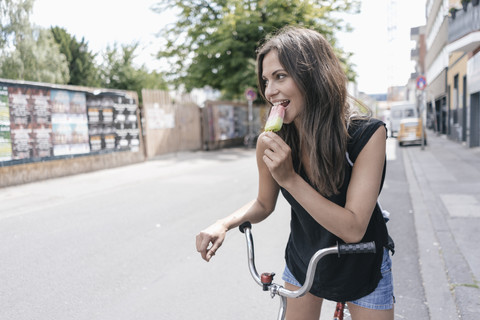 Woman with bicycle eating ice lolly stock photo