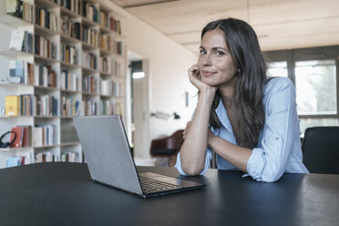 Portrait of smiling woman sitting at table with laptop - JOSF01608