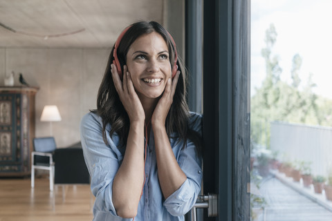 Smiling woman listening to music at home stock photo