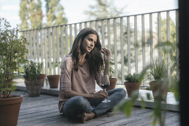 Woman with glass of red wine relaxing on balcony - JOSF01616