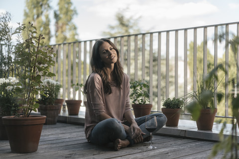 Woman with glass of red wine relaxing on balcony stock photo