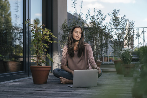 Woman with laptop sitting on balcony stock photo