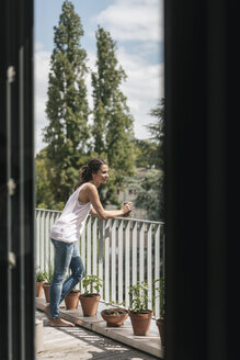 Lächelnde Frau entspannt sich auf dem Balkon - JOSF01629