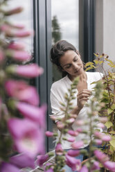 Woman caring for plant on balcony - JOSF01636