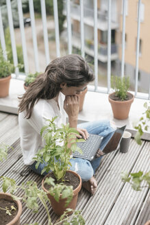 Frau mit Laptop auf dem Balkon sitzend - JOSF01638